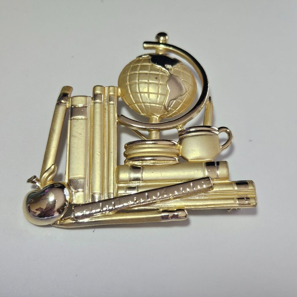 AJC gold tone books and globe brooch